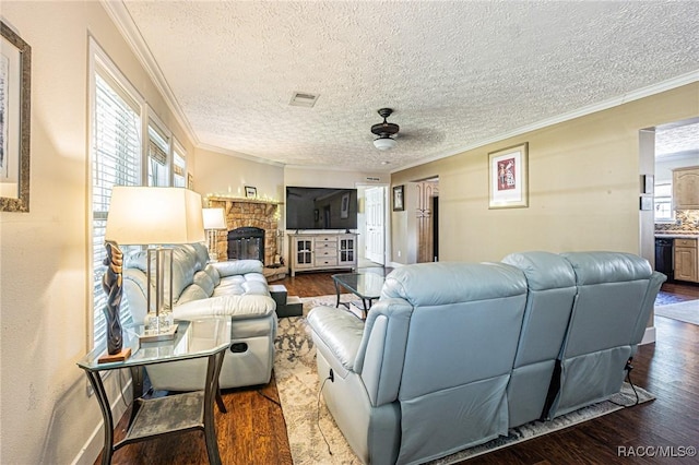 living room with a stone fireplace, crown molding, a textured ceiling, ceiling fan, and hardwood / wood-style floors