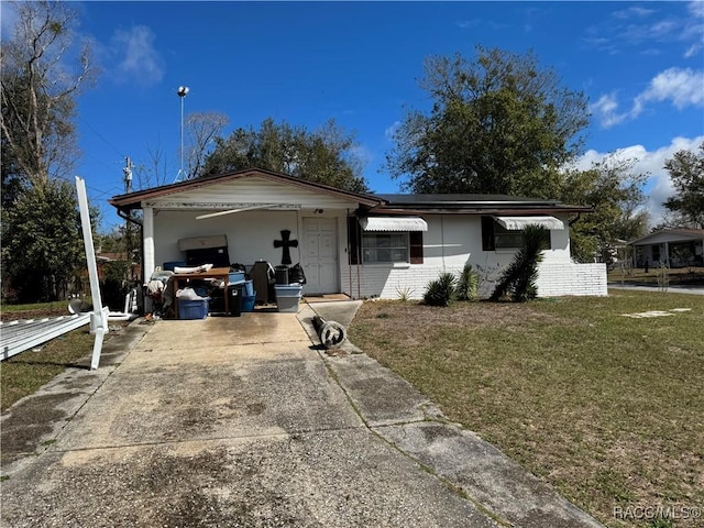 ranch-style home featuring concrete driveway, brick siding, and a front yard