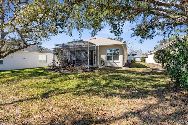 rear view of property featuring a yard and glass enclosure