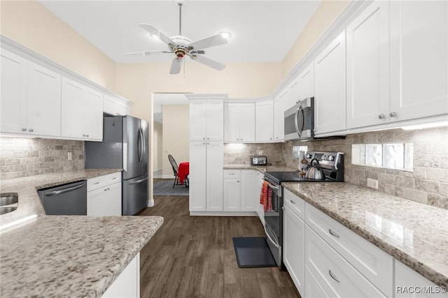 kitchen with appliances with stainless steel finishes, white cabinetry, light stone counters, tasteful backsplash, and dark hardwood / wood-style flooring