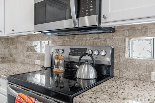 kitchen with stainless steel appliances, light stone countertops, and white cabinets