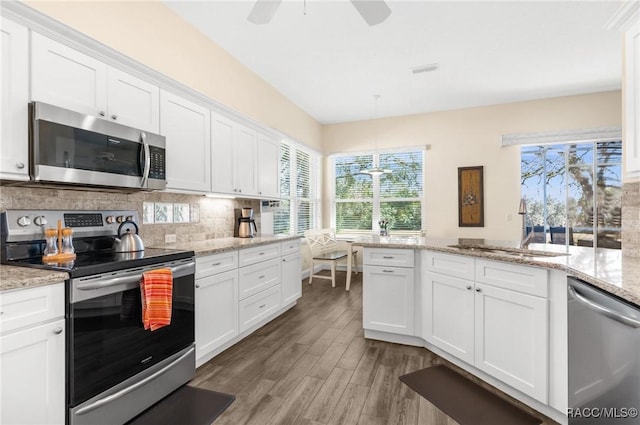 kitchen with sink, white cabinetry, light stone counters, tasteful backsplash, and stainless steel appliances