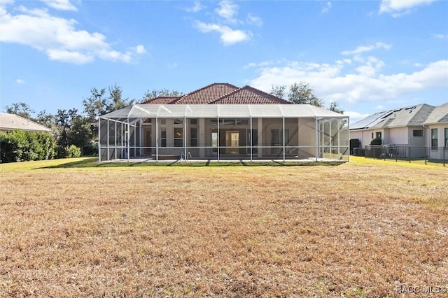 rear view of property featuring a lawn and glass enclosure