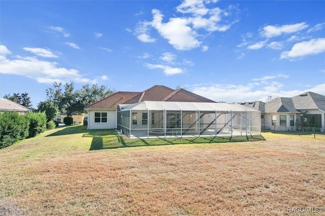 back of house with glass enclosure and a yard