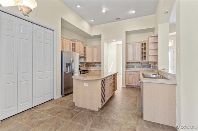 kitchen featuring sink, a center island, tasteful backsplash, light brown cabinetry, and appliances with stainless steel finishes