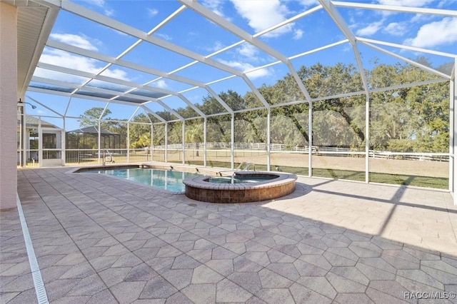 view of pool featuring glass enclosure, an in ground hot tub, and a patio