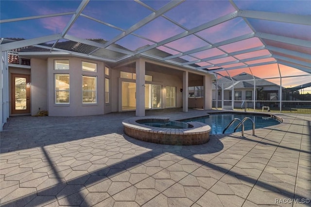 pool at dusk featuring a lanai, an in ground hot tub, and a patio