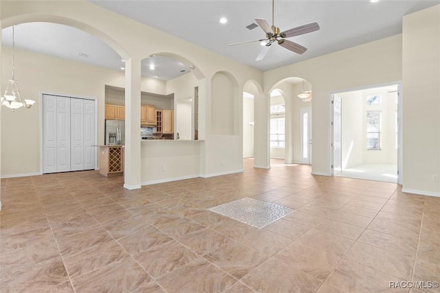 unfurnished living room with light tile patterned flooring and ceiling fan with notable chandelier