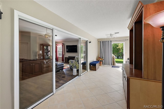 doorway with light tile patterned floors, a textured ceiling, and ceiling fan