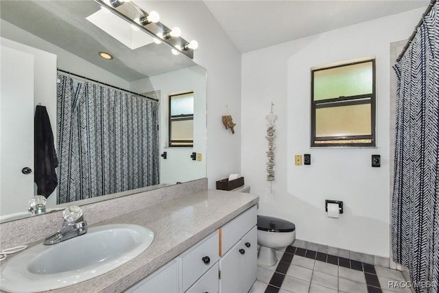 bathroom featuring tile patterned flooring, vanity, a skylight, and toilet