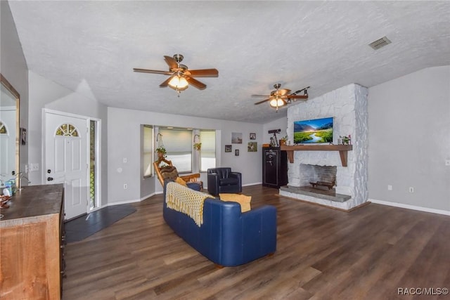 living room featuring a stone fireplace, lofted ceiling, dark hardwood / wood-style flooring, ceiling fan, and a textured ceiling