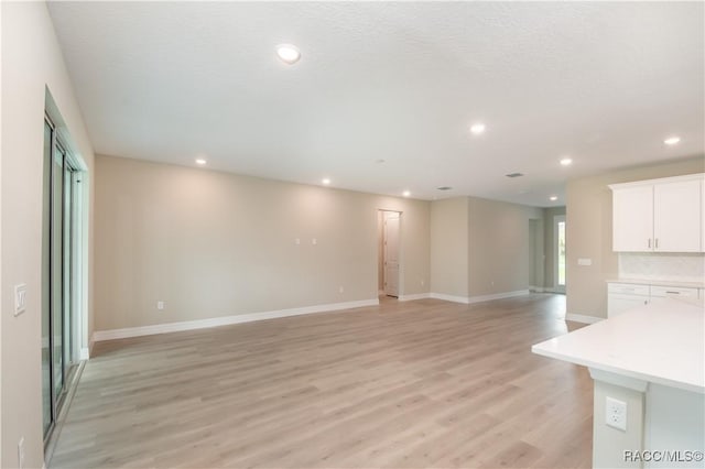 unfurnished living room with light hardwood / wood-style floors and a textured ceiling