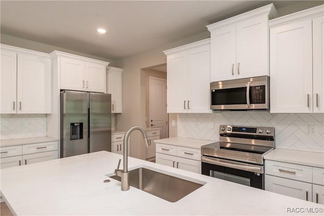 kitchen with sink, appliances with stainless steel finishes, white cabinetry, and decorative backsplash