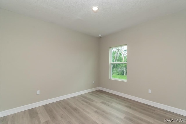 spare room with light hardwood / wood-style flooring and a textured ceiling