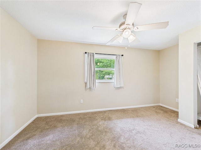 carpeted spare room featuring ceiling fan and baseboards