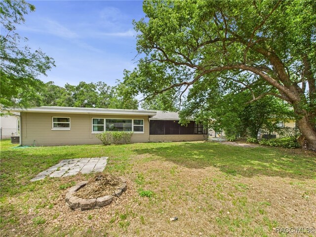back of property with a sunroom, a lawn, and central AC unit