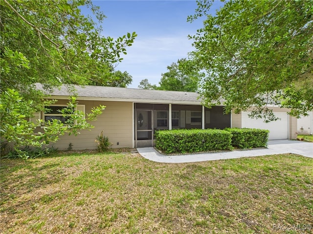 single story home featuring concrete driveway, a sunroom, a front yard, an attached garage, and a shingled roof
