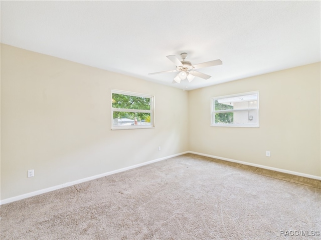 carpeted empty room featuring plenty of natural light, ceiling fan, and baseboards