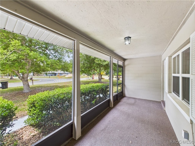 unfurnished sunroom featuring a textured ceiling, carpet, and a water view