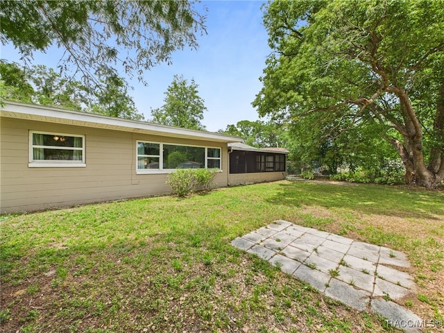 view of green lawn with a sunroom