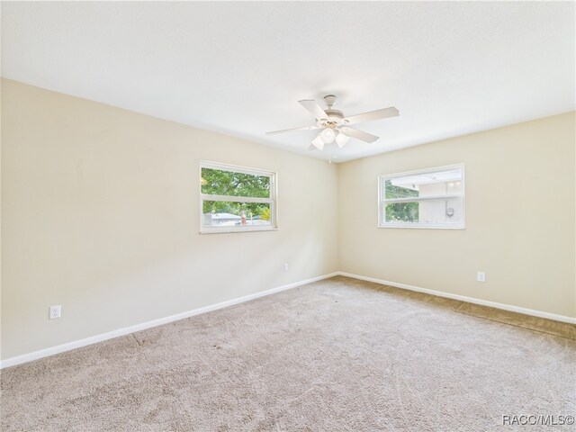 carpeted empty room featuring plenty of natural light, ceiling fan, and baseboards