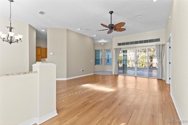 unfurnished living room with ceiling fan with notable chandelier, a textured ceiling, french doors, and light hardwood / wood-style flooring