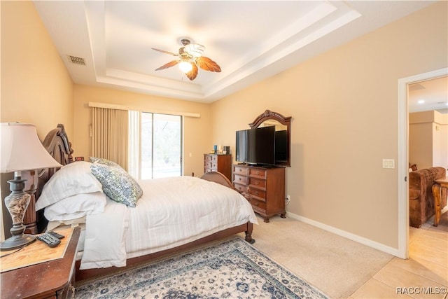 bedroom featuring ceiling fan, tile patterned floors, a raised ceiling, and access to outside