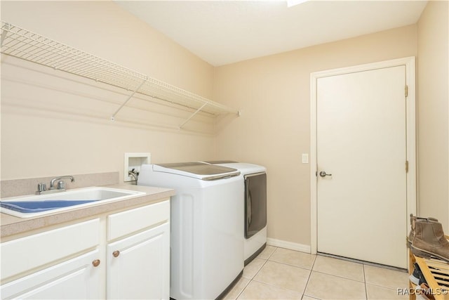 laundry area with cabinets, separate washer and dryer, sink, and light tile patterned floors