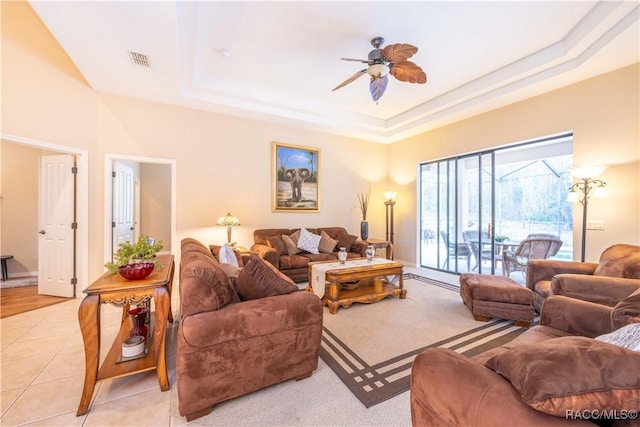 tiled living room featuring ceiling fan and a tray ceiling