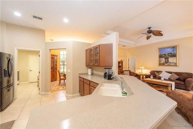 kitchen featuring fridge with ice dispenser, sink, light tile patterned floors, and kitchen peninsula