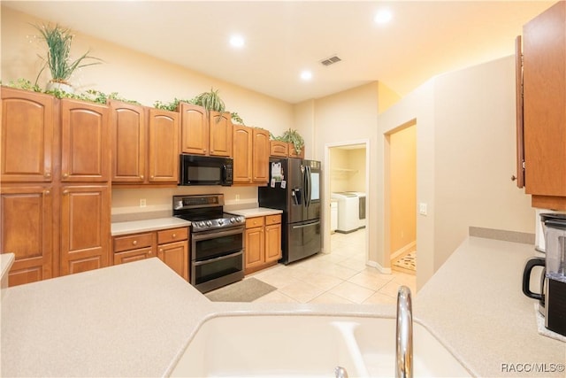 kitchen with light tile patterned flooring, appliances with stainless steel finishes, sink, and washing machine and dryer