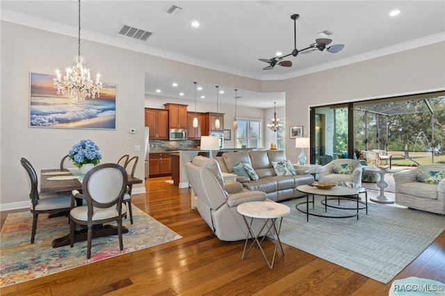 living room featuring ceiling fan with notable chandelier, dark hardwood / wood-style flooring, and ornamental molding