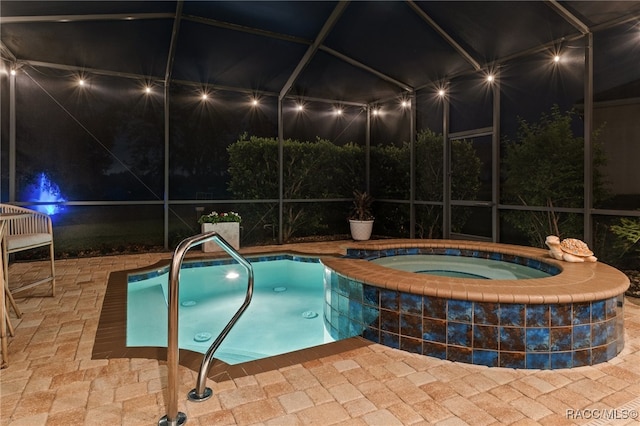 pool at twilight featuring an in ground hot tub