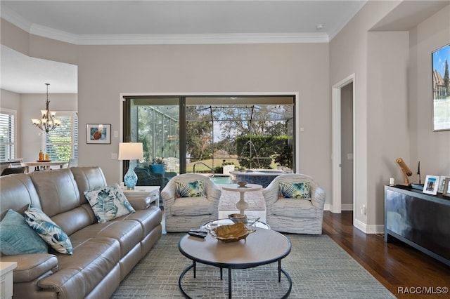 living room featuring a notable chandelier, ornamental molding, and dark wood-type flooring