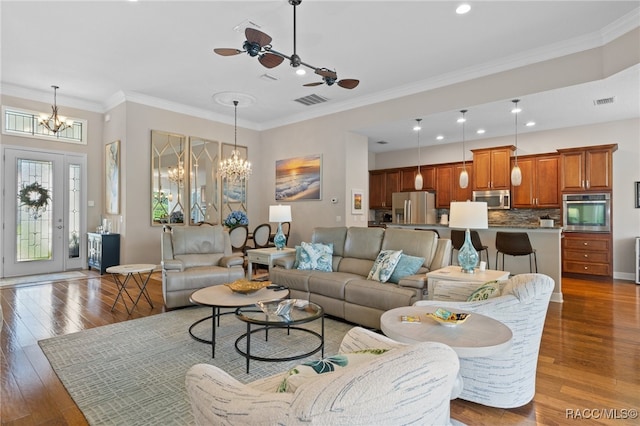 living room with ceiling fan with notable chandelier, ornamental molding, and dark wood-type flooring