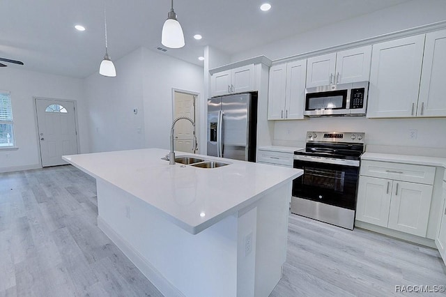 kitchen featuring white cabinetry, sink, decorative light fixtures, a center island with sink, and appliances with stainless steel finishes