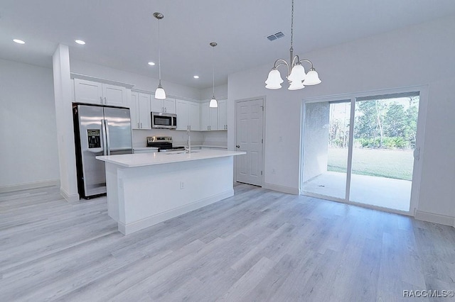 kitchen with appliances with stainless steel finishes, pendant lighting, an inviting chandelier, light hardwood / wood-style flooring, and white cabinetry