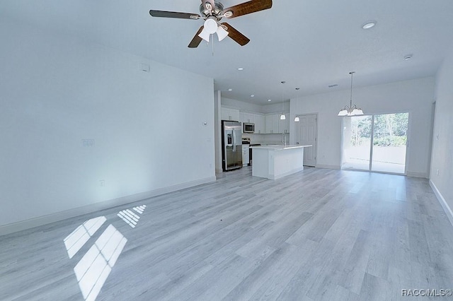 unfurnished living room featuring light hardwood / wood-style flooring, ceiling fan with notable chandelier, and sink