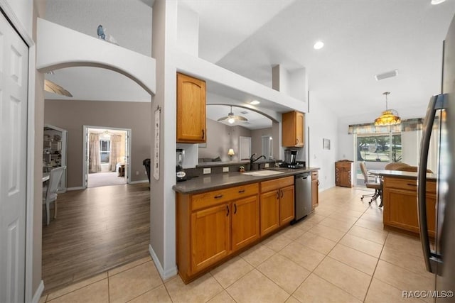 15776 SW 11th Terrace Rd, Ocala, FL 34473 - kitchen with stainless steel dishwasher, dark countertops, brown cabinets, light tile patterned flooring, and arched walkways