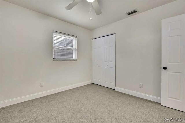 657 NE 11th St, Crystal River, FL 34428 - unfurnished bedroom with baseboards, light carpet, a closet, and ceiling fan