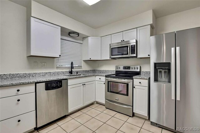 657 NE 11th St, Crystal River, FL 34428 - kitchen featuring stainless steel appliances, a sink, white cabinets, light tile patterned floors, and light stone countertops