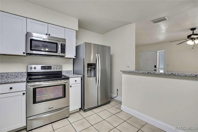 657 NE 11th St, Crystal River, FL 34428 - kitchen featuring appliances with stainless steel finishes, white cabinetry, light tile patterned flooring, and light stone counters