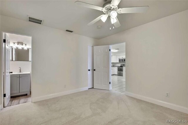657 NE 11th St, Crystal River, FL 34428 - unfurnished bedroom with light carpet, baseboards, connected bathroom, and ceiling fan