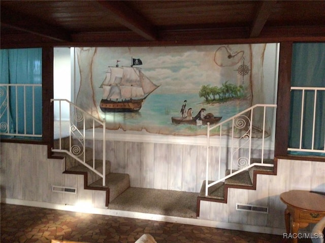 stairway featuring beamed ceiling, wooden walls, and wood ceiling