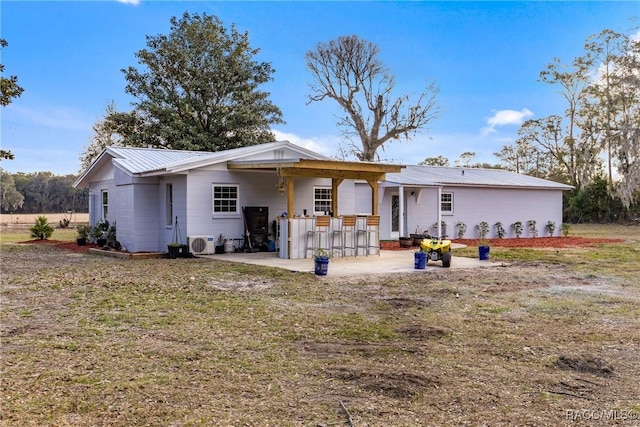 rear view of house featuring exterior bar, a yard, and a patio area