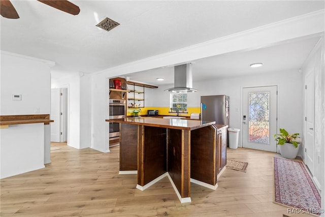 kitchen featuring sink, light hardwood / wood-style flooring, ceiling fan, appliances with stainless steel finishes, and island range hood