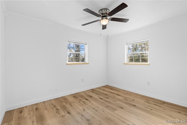 empty room featuring ornamental molding, light wood-type flooring, and a wealth of natural light