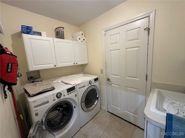 clothes washing area featuring cabinets, washing machine and dryer, and light tile patterned floors