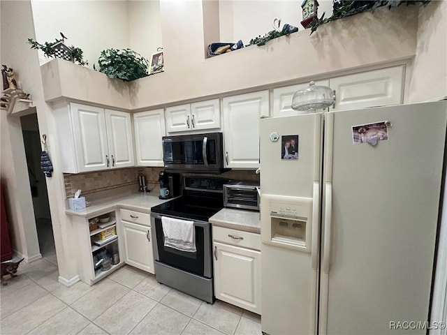 kitchen with white cabinetry, stainless steel appliances, light tile patterned floors, and a towering ceiling