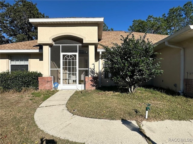 view of exterior entry with a lawn